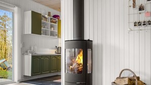 A modern kitchen with a wood-burning stove, open shelving, and a wicker basket. - "Ruka" - 600m from the sea by Interhome (Løkken)