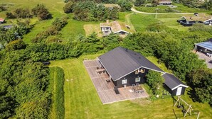 An aerial view of a residential area with a house featuring a large deck, surrounded by lush greenery and a clear view of the ocean. - "Ruka" - 600m from the sea by Interhome (Løkken)