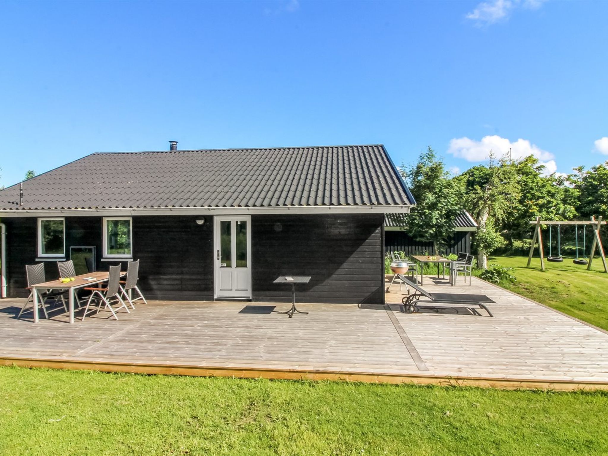 Une maison moderne dotée d’une terrasse, d’un coin repas et d’un jardin.