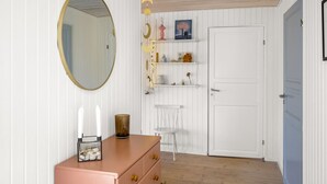 A room with a white door, a pink dresser, a round mirror, and shelves with decorative items. - "Ruka" - 600m from the sea by Interhome (Løkken)