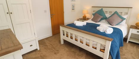 A bedroom with a bed, bedside tables, a wooden bench, a wardrobe, and a door.