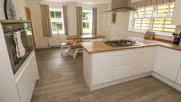 A modern kitchen with a central island, white cabinetry, and a built-in oven.