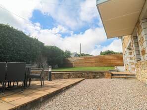 Un patio con mobiliario exterior, un muro de piedra y vistas a un campo verde.