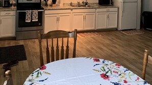 Une cuisine avec des meubles blancs, une cuisinière, un four à micro-ondes et un réfrigérateur.