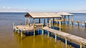 A wooden pier extending into calm waters with a covered seating area and a small shelter. - Pet-Friendly Cottage with Private Beach Access & Pier in Dauphin Island, Alabama (Dauphin Island)