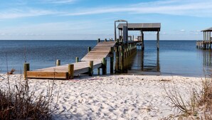 A wooden pier extending into calm waters, a wooden structure at the end, and a sandy beach. - Pet-Friendly Cottage with Private Beach Access & Pier in Dauphin Island, Alabama (Dauphin Island)