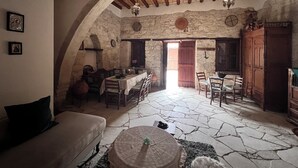 Un interno rustico con pareti in pietra, travi in legno, una zona pranzo e un angolo salotto accogliente.