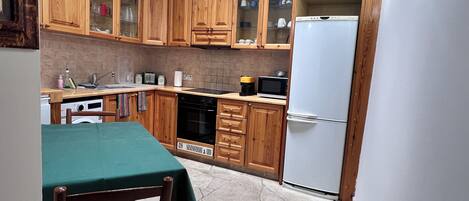 A compact kitchen with wooden cabinets, a microwave, a dishwasher, and a refrigerator.