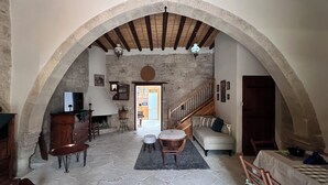 Un soggiorno ad arco con pavimento in pietra, un camino, un divano e una scala che conduce a un altro livello.
