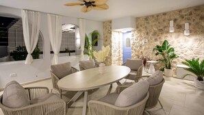 A dining area with wicker chairs, a round table, and a ceiling fan. - Nama Summer Retreat Mikra Mantinia Beachfront Gem (Kalamata)
