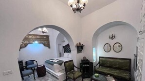 A room with a bed, two chairs, a sofa, a small table, and a decorative mirror on the wall. - Guesthouse DarHamdoun (Hammam Al Agzaz)