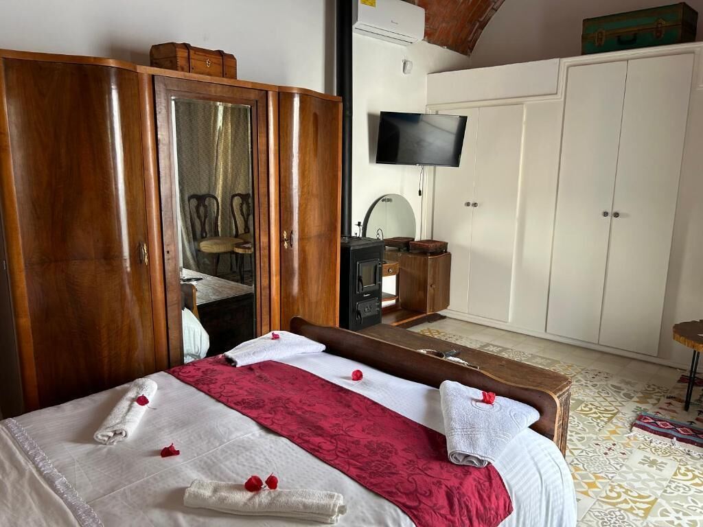 A hotel room with a bed, wooden wardrobe, television, and a desk.