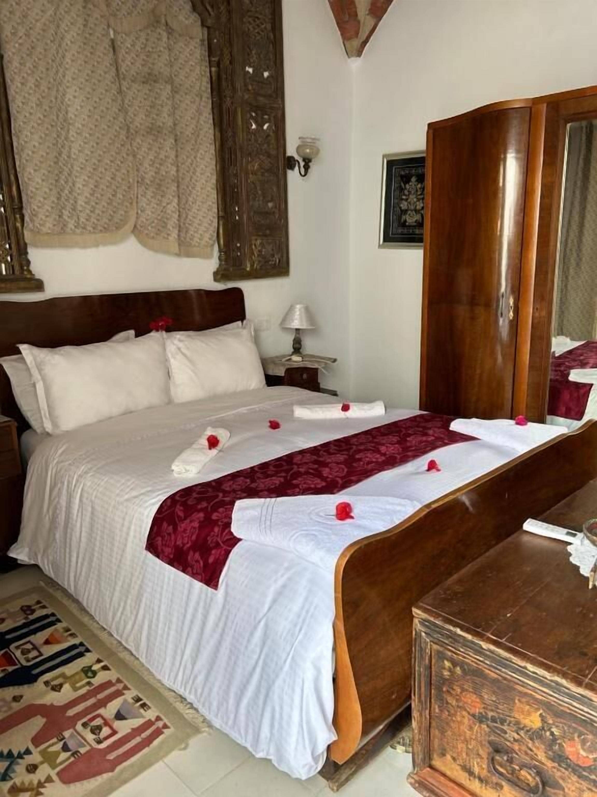 Ein Schlafzimmer mit einem großen Bett, einem Holzschrank, einem Nachttisch und einem Spiegel.