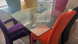 Ein Konferenztisch mit Glasplatte, umgeben von Stühlen in verschiedenen Farben.