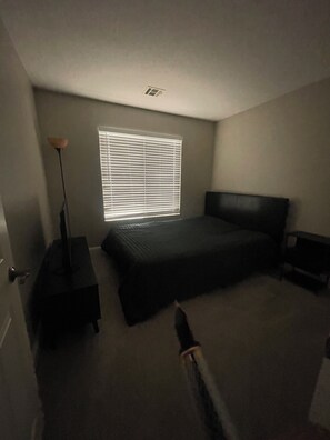 A bedroom with a bed, a nightstand, a lamp, and a window with blinds. - Awesome 4-bedroom house with AC in vibrant Las Vegas (Las vegas)