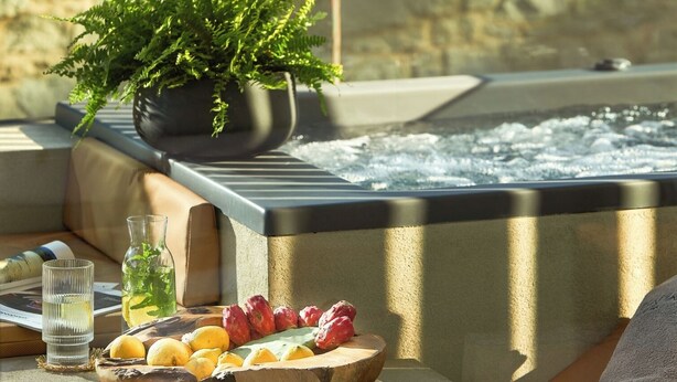 Ein Whirlpool mit einem Blumentopf, einer Obstschale und einem Glas Wasser auf einem Tisch.