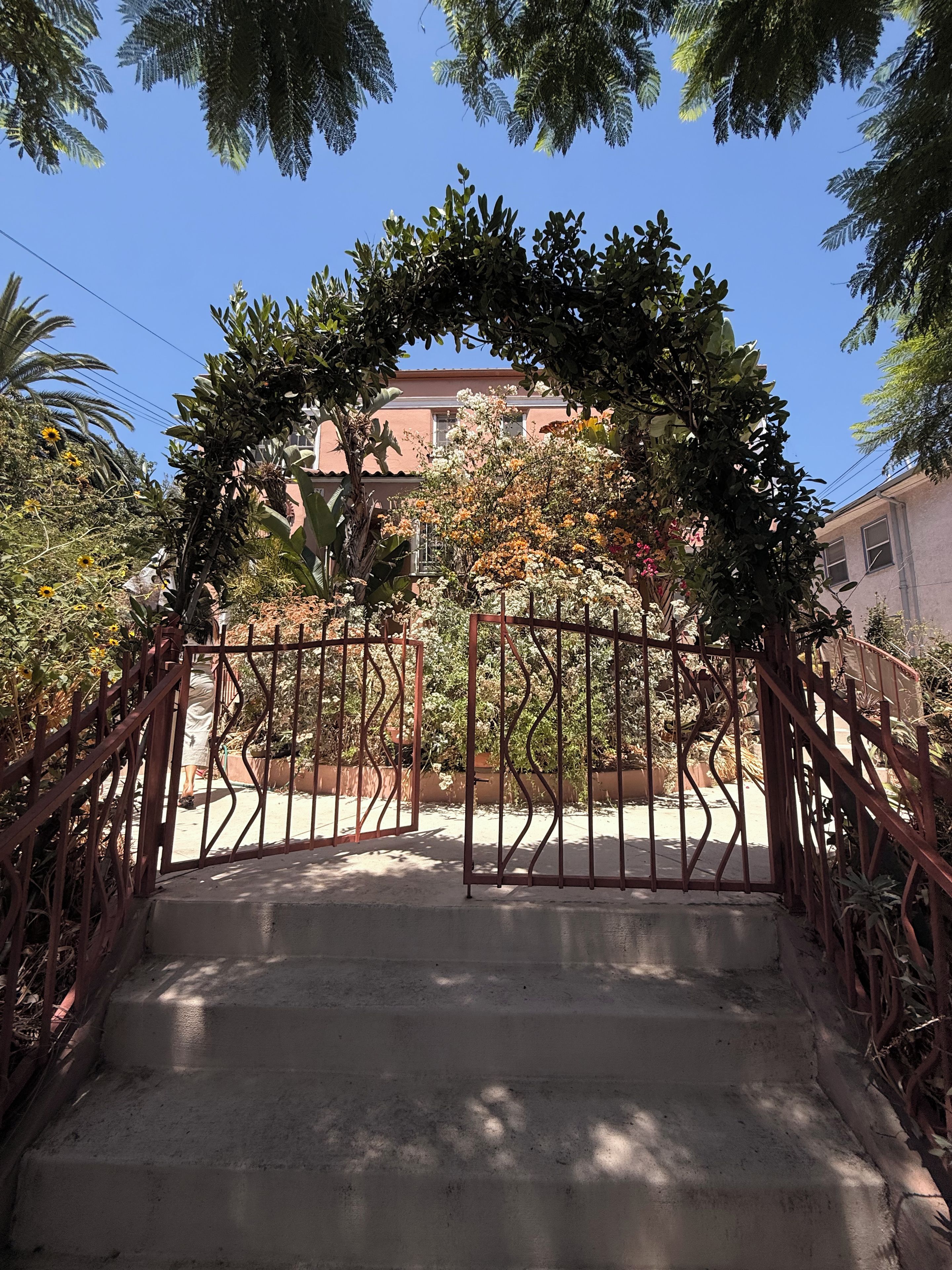 A gated entrance with a concrete staircase leading to a building with a red roof.
