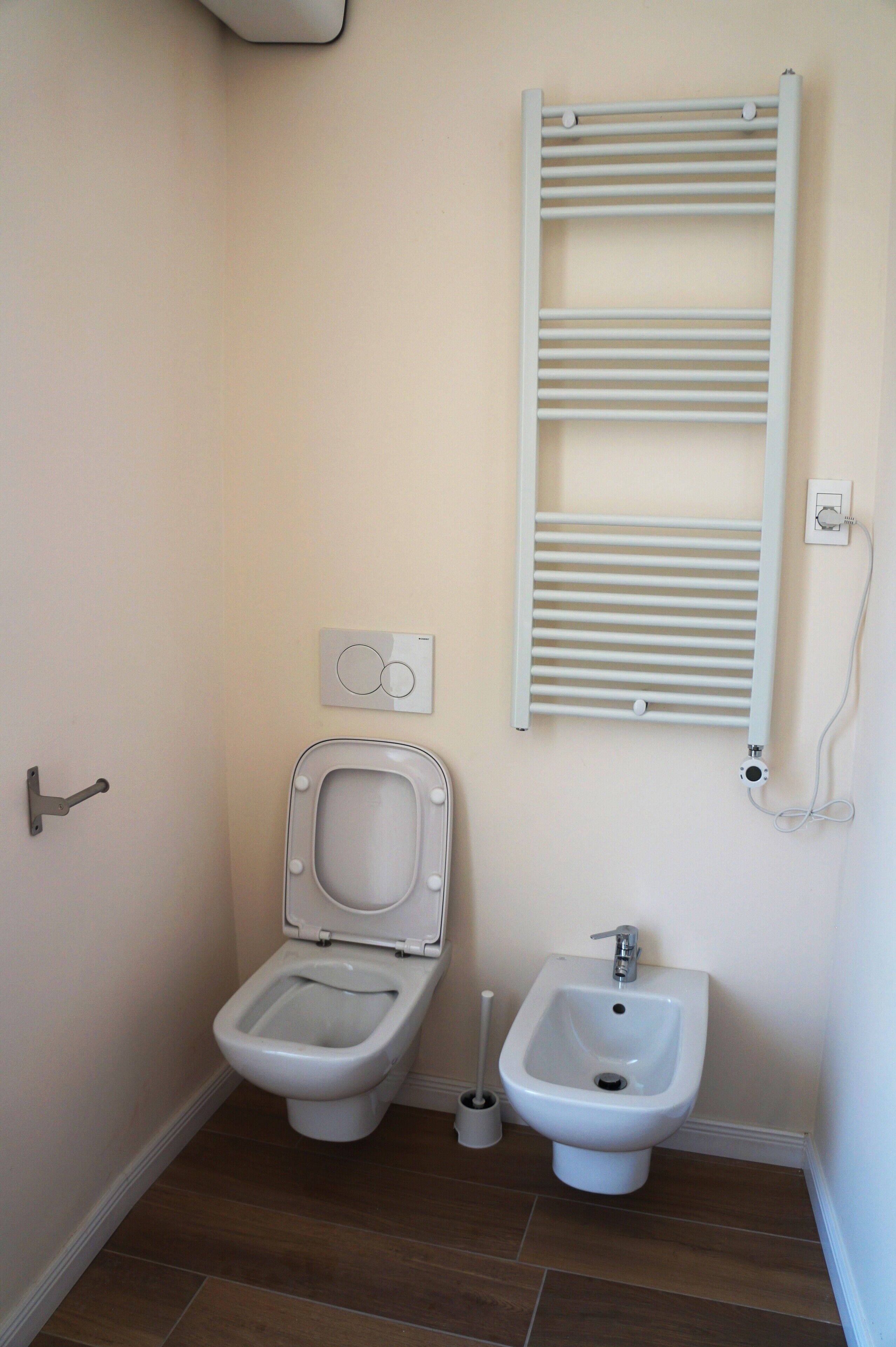 A bathroom with a toilet, bidet, and a towel rack.