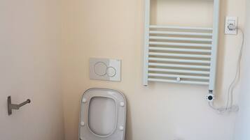 A bathroom with a toilet, bidet, and a towel rack.