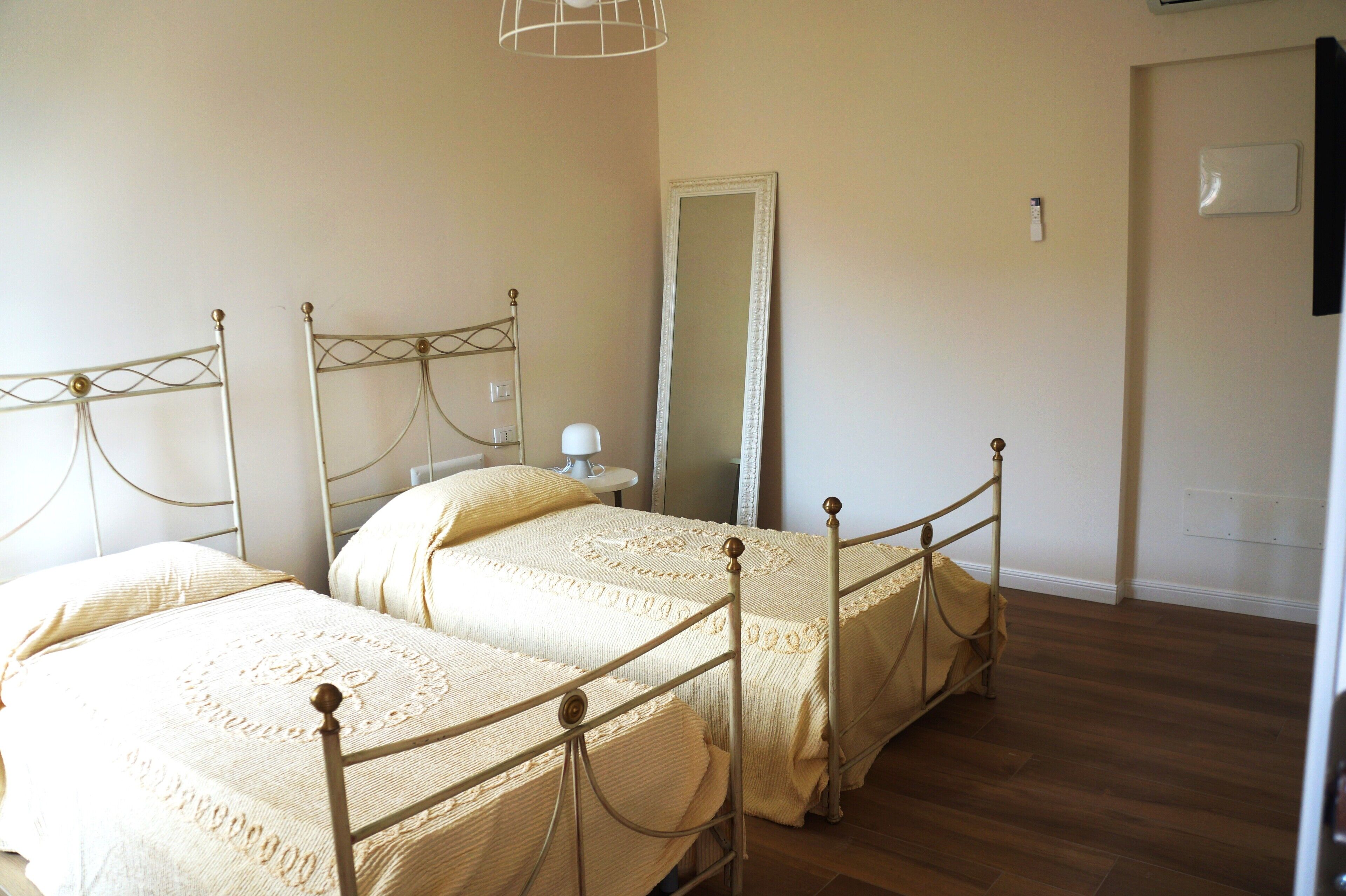 Ein Schlafzimmer mit zwei Betten, einem Spiegel und einer Tür.