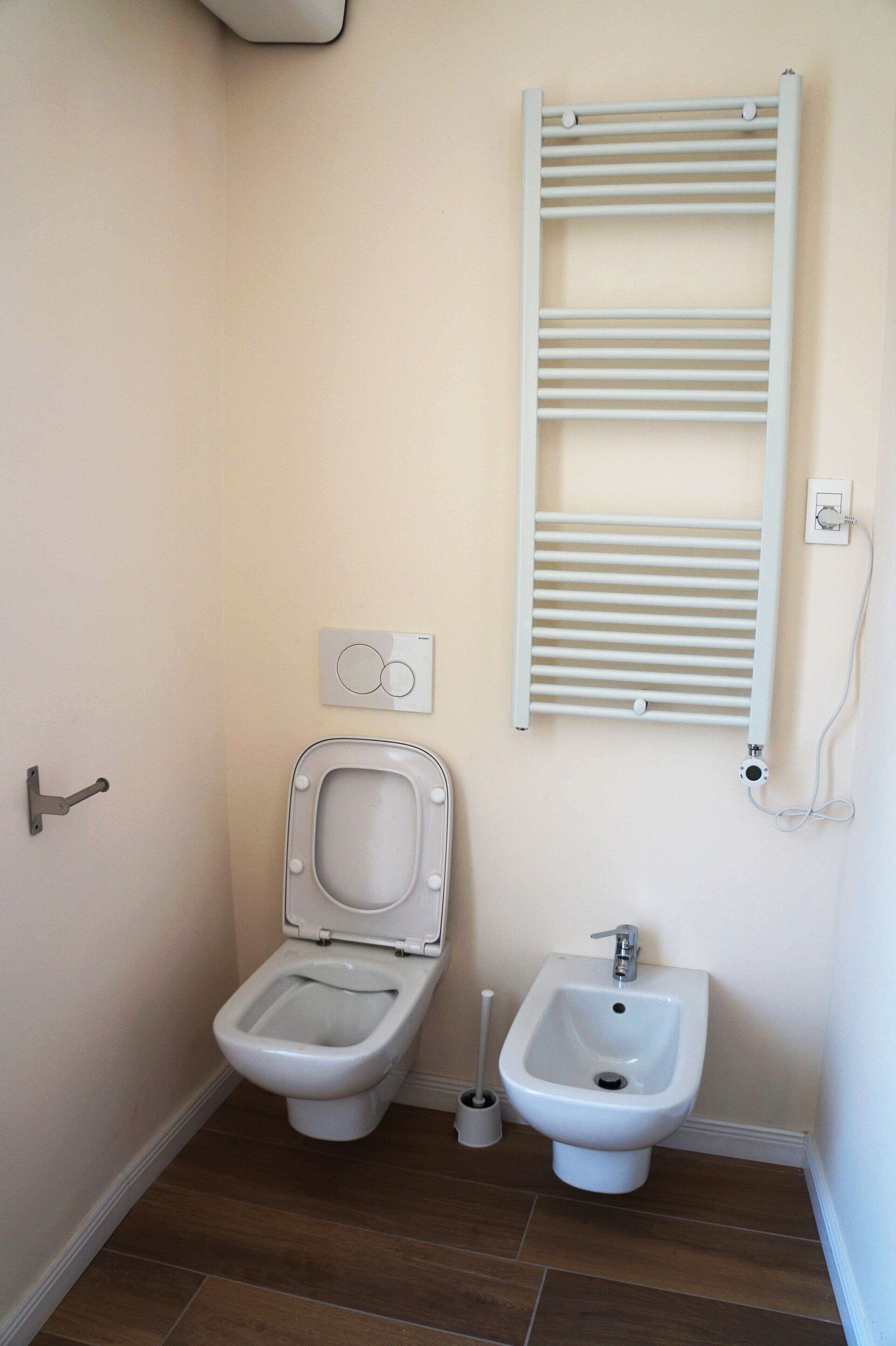 Ein kleines Badezimmer mit Toilette, Bidet und Handtuchhalter.