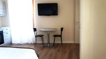Une chambre d’hôtel avec un lit, une petite table, deux chaises, un téléviseur fixé au mur et une porte.