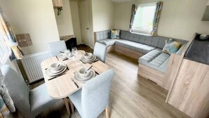 Un espacio habitable moderno y funcional, con zona de comedor, asientos y kitchenette.