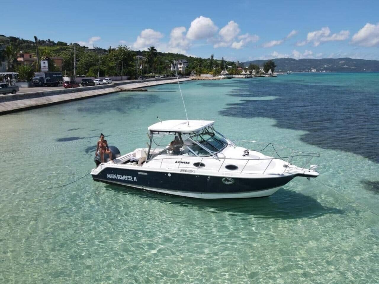 Un barco llamado 'MAIN SHIP 2' atracado en un puerto deportivo con agua turquesa cristalina.