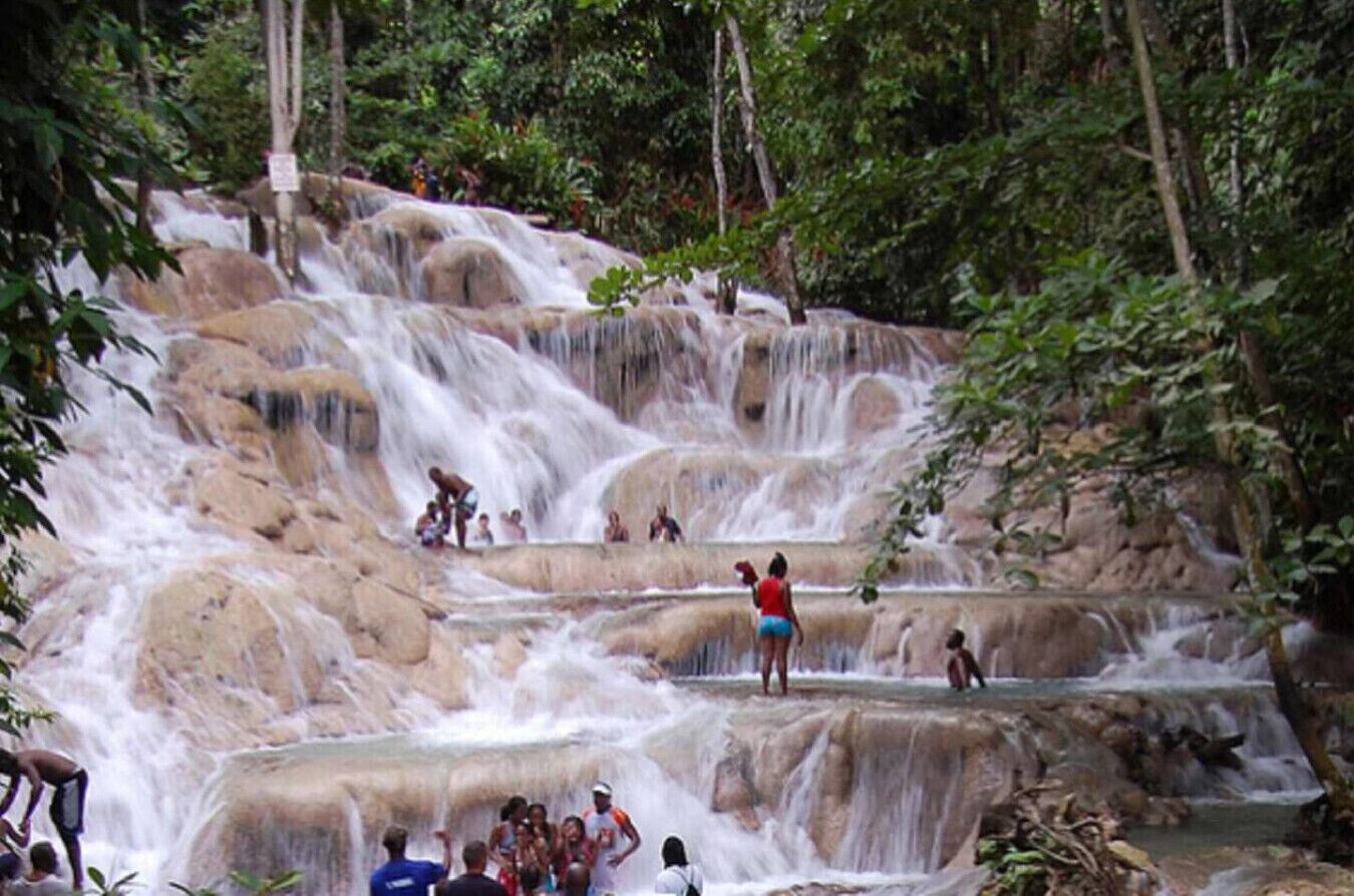 A natural waterfall with multiple tiers, surrounded by lush greenery.