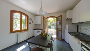 A kitchen with a dining table, chairs, a refrigerator, and a window with a view of greenery. - Detached house, 2.000m² with garden, orchard. Four-room apt 123m², ground floor. (Arenella)