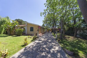 A pathway leading to a building with a yellow facade, surrounded by greenery and potted plants. - Detached house, 2.000m² with garden, orchard. Four-room apt 123m², ground floor. (Arenella)
