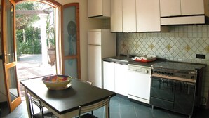 A kitchen with a dining table, a refrigerator, a stove, and a window with a view of greenery. - Detached house, 2.000m² with garden, orchard. Four-room apt 123m², ground floor. (Arenella)