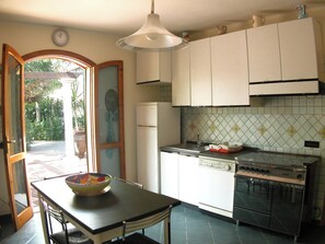 A kitchen with a dining table, a refrigerator, a stove, and a window with a view of greenery. - Detached house, 2.000m² with garden, orchard. Four-room apt 123m², ground floor. (Arenella)