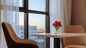 A room with two chairs, a table, and a window with a view of buildings.