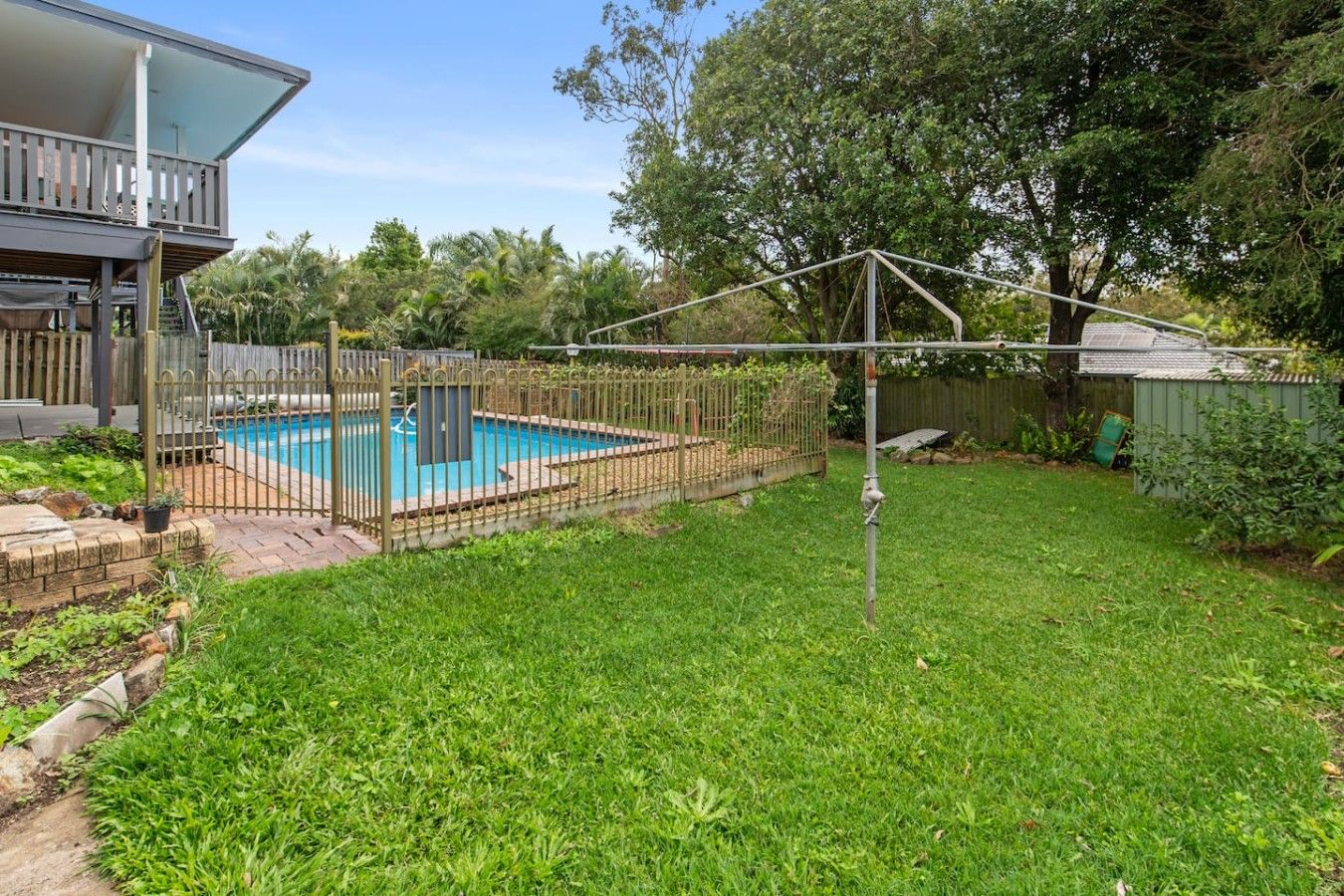 A backyard with a swimming pool, a fenced area, and a wooden deck.