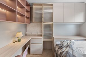 Une chambre à coucher de taille réduite, comprenant un bureau, des étagères et un lit.