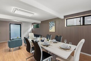 A modern dining room with a white table set for six, surrounded by dark and light chairs. - Affordable Family Retreat | Pool & Prime Location (MacGregor)