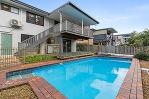Ein Wohnhaus mit Schwimmbad, überdachter Terrasse und umzäunter Garten.