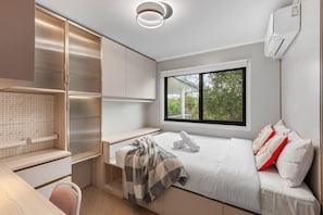 Ein modernes Schlafzimmer mit Bett, Schreibtisch und Kleiderschrank.