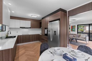 Eine moderne Küche mit Einbaukühlschrank, Holzschränken und einem Essbereich mit Tisch für vier Personen.