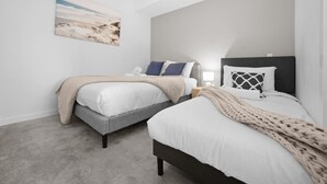 Ein Schlafzimmer mit zwei Betten, einem Nachttisch, einer Lampe und einem Gemälde an der Wand.