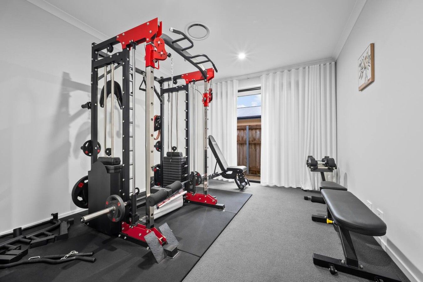 A home gym with a squat rack, bench, and various weights.