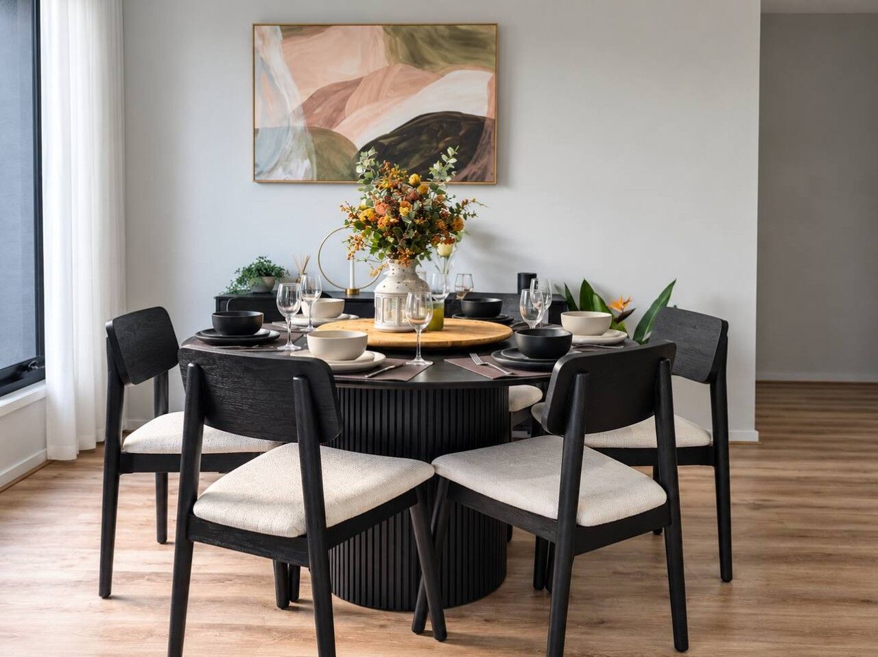 Ein Essbereich mit einem runden Tisch, vier Stühlen und einem Blumenstrauß.