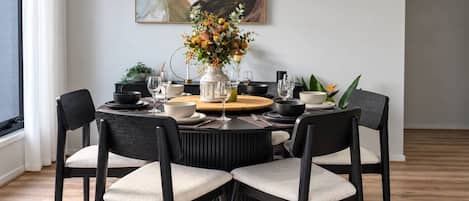 Un comedor con una mesa redonda, cuatro sillas y un jarrón de flores.