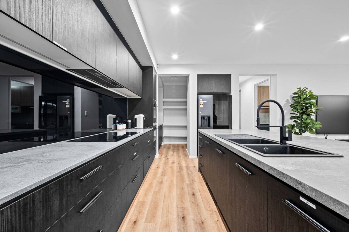 A modern kitchen with dark cabinetry, a central island, and a built-in stove.