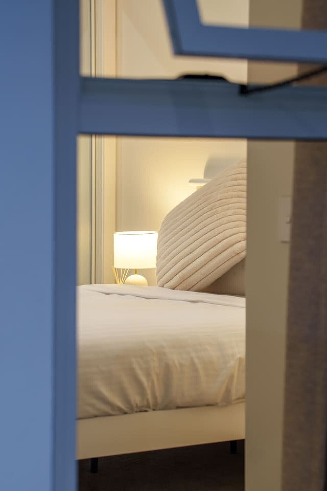 A hotel room with a bed, a bedside lamp, and a window.