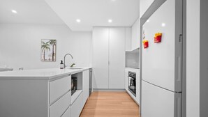 A modern kitchen with white cabinetry, a wooden floor, and a central island with a sink and faucet.