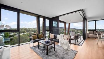 A modern living room with large windows, a sofa, a coffee table, and a view of the landscape.