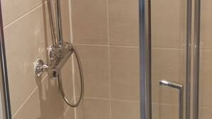 Een douchecabine met glazen wanden, een handdouche en een vaste douchetuit.
