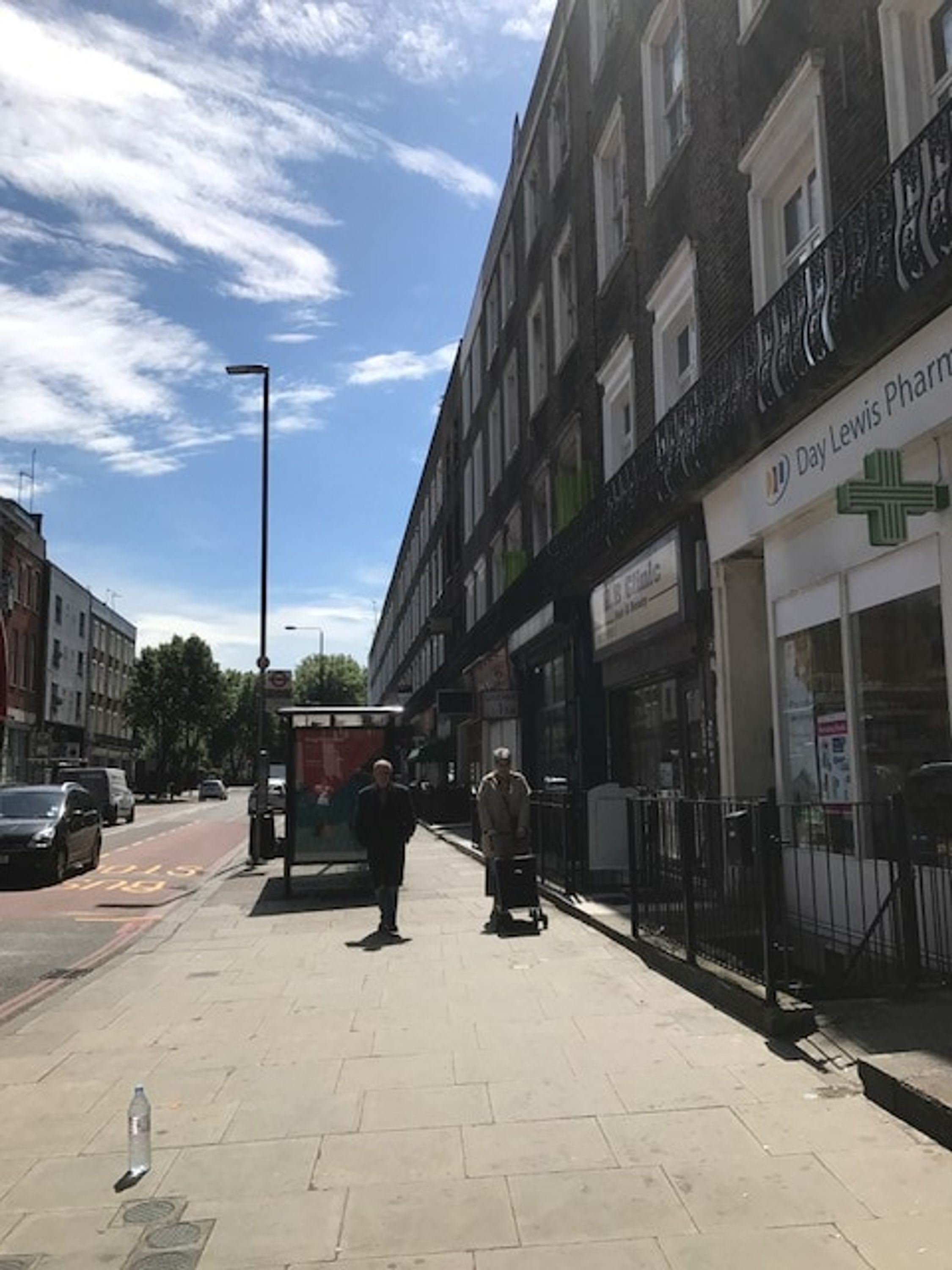 A street with a pharmacy named 'Day Lewis Pharmacy' on the right.